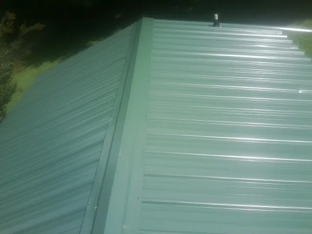 New green metal panels meeting at the ridge of a roof — Flat Roof Repair work by our crew in Hot Springs Village