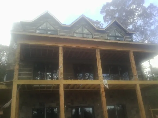 Dormers and porch framing on a large log home under construction — Roof Coating work by our crew in Hot Springs Village