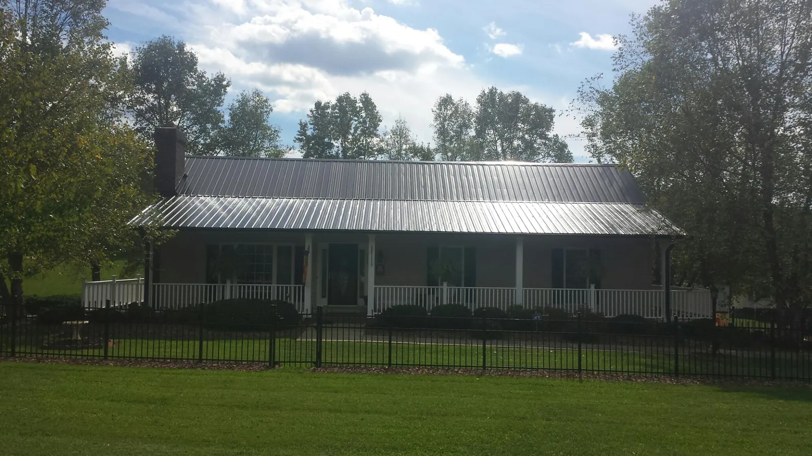 Gray metal roof on a brick ranch with a full width front porch — Gutter Guard Installation work by our crew in Hot Springs Village