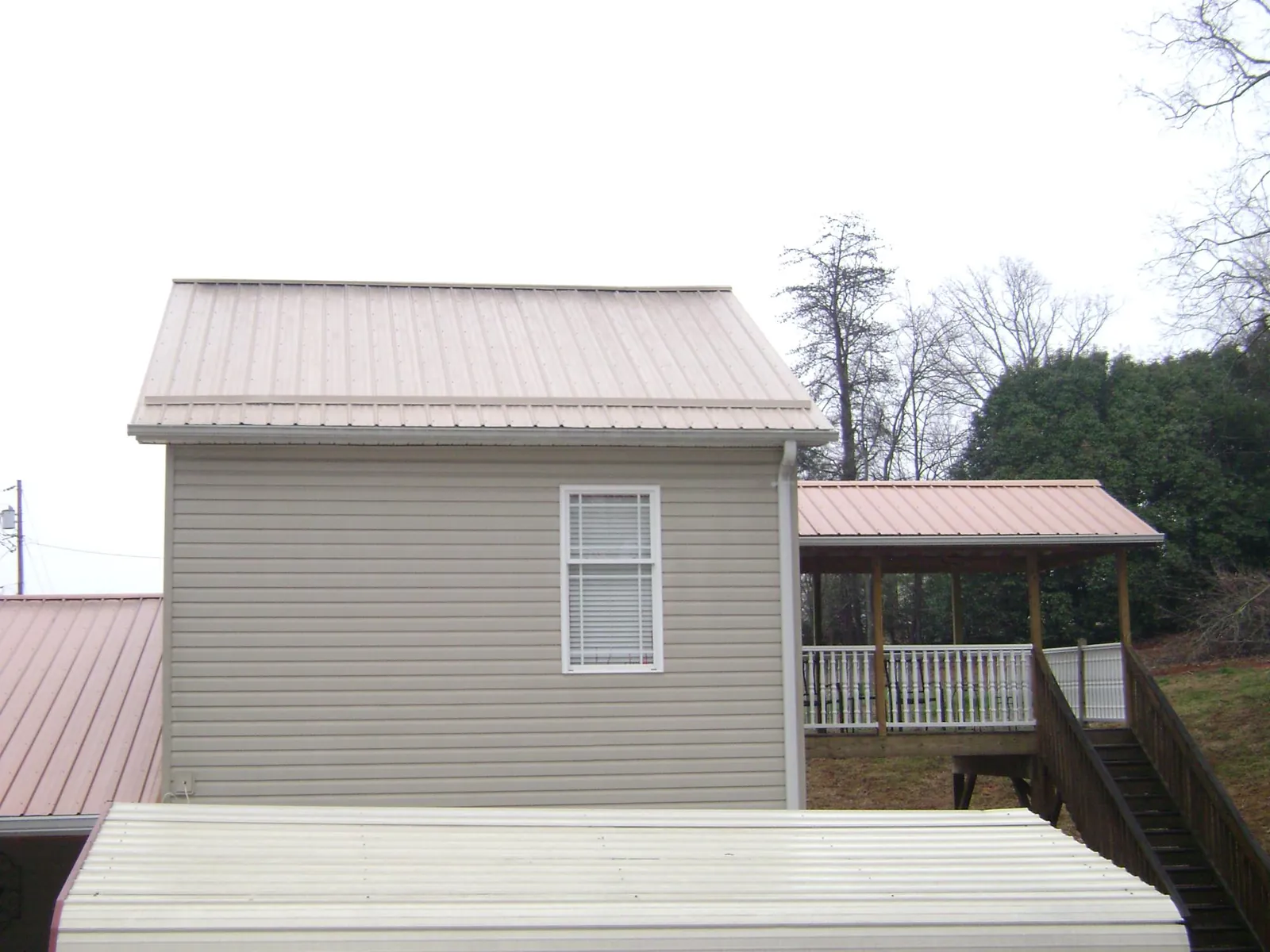 Tan metal roofs on a two story addition and attached porch, from a Roof Replacement job in Hot Springs Village