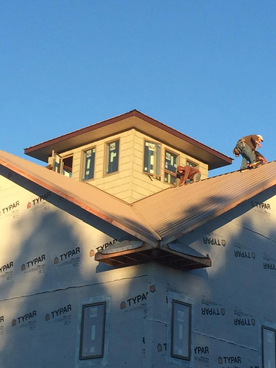 Roofers working around a rooftop cupola on a new metal roof at sunset — Roof Waterproofing in Hot Springs Village by Roofing Brothers